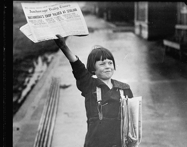 A newsboy holding up a newspaper