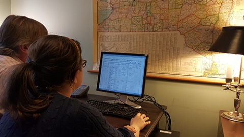 Two people sit in front of a computer, working on a genealogy and technology project. 